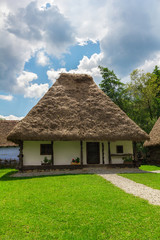 Fototapeta na wymiar traditional old romanian country house with thatched roof with nice cloudy blue sky on background
