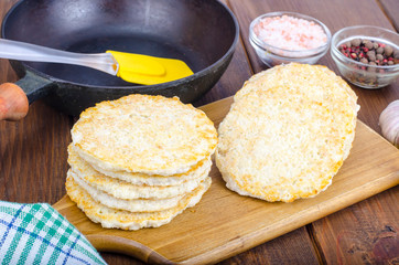 Frozen raw potato pancakes on cutting board for cooking