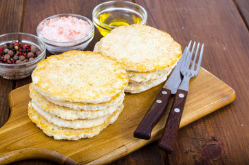 Frozen raw potato pancakes on cutting board for cooking