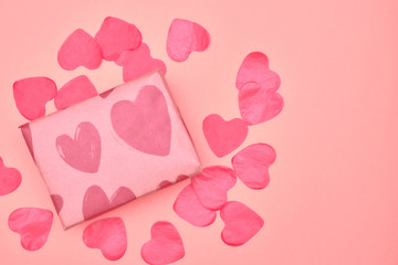 Gift in Kraft paper with red hearts on pink background with hearts. The Concept Of Valentine's Day. view from above . copy space.