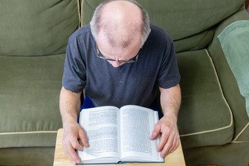 over head view of balding man reading a book.