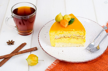 Piece of mango mousse cake on plate, white wooden table
