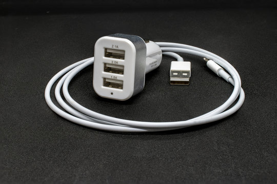 Three port USB car cigarette adapter and cable on a dark grey background
