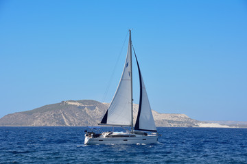 the yacht with a sail at the sea near the island