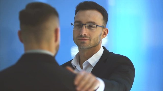 The two businessmen pat shoulder on the blue background. slow motion