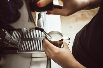 Naklejka premium The barista is making boiled milk. He uses special coffee machine for it.