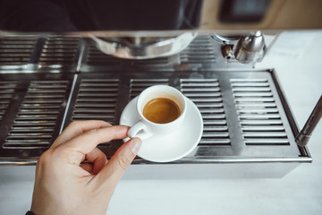 close-up view of glass cup with cappuccino and coffee machine