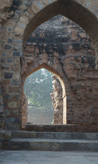 New Delhi, India's ruins from the Mogul Empire, created a beautiful view through a stone archway to a garden illuminated by the morning sun..