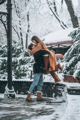 young guy and beautiful girl kiss in a snowy park