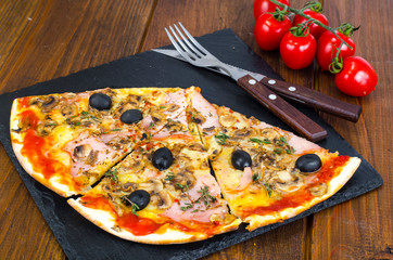 Pizza with Mozzarella cheese, ham, tomato sauce, salami, pepper, spices on wooden table background