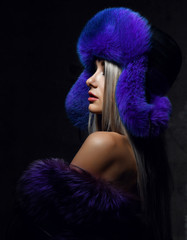 Portrait of young beautiful woman in blue purple fashion arctic fox winter fur ear flap hat 