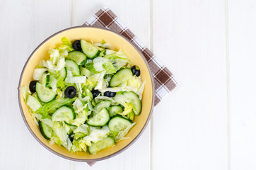 Healthy food. Vegetarian salad from iceberg, fresh cucumber and black olives