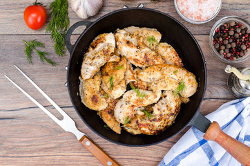 Pan with fried chicken pieces, wooden background