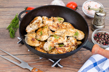 Pan with fried chicken pieces, wooden background