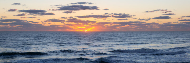 Panoramic view of the ocean during a vibrant cloudy sunrise. Taken in Daytona Beach, Florida, United States.