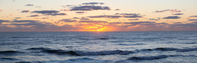 Panoramic view of the ocean during a vibrant cloudy sunrise. Taken in Daytona Beach, Florida, United States.