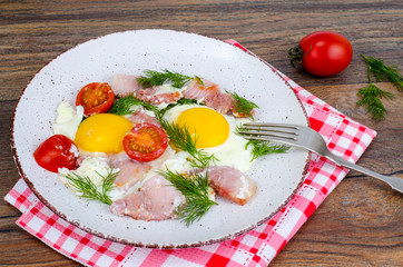 Plate with fried eggs,ham and tomatoes for breakfast