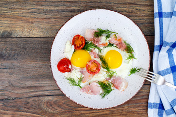 Plate with fried eggs,ham and tomatoes for breakfast