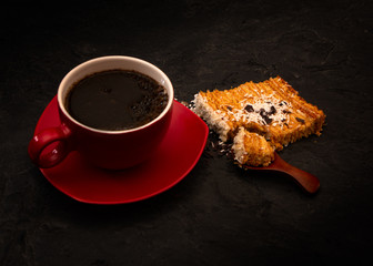 coffee in a red cup and homemade honey cake on dark background