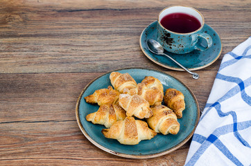 Homemade mini croissants with sugar and cinnamon, wooden background