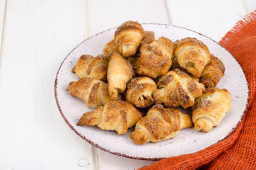 Homemade mini croissants with sugar and cinnamon, wooden background