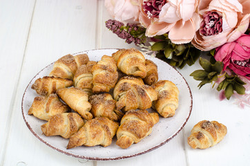 Homemade mini croissants with sugar and cinnamon, wooden background