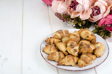 Homemade mini croissants with sugar and cinnamon, wooden background