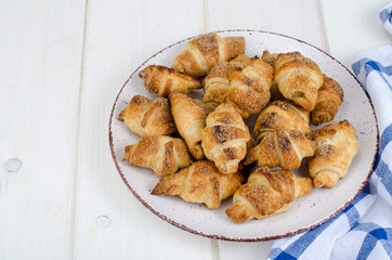 Homemade mini croissants with sugar and cinnamon, wooden background