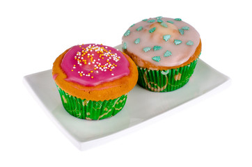 Two homemade mini cupcakes with colored icing