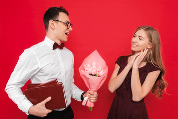 A handsome student, wearing glasses, gives a gift and a bouquet of flowers to his girlfriend...