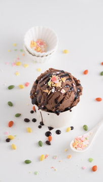 Chocolate ice cream scoop toppine with chocolate sauce and cake decoration called flake rainbow