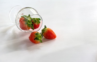 Fresh strawberry in the glass cup on dark white background