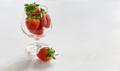 Fresh strawberry in the glass cup on dark white background