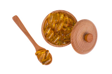 Yellow vitamin soft gelatin capsules with oily drug and nutritional supplement, wooden spoons, scoop