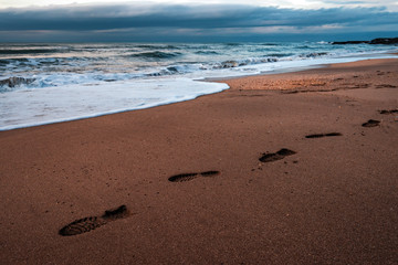 Footprints in the sand by the stormy sea