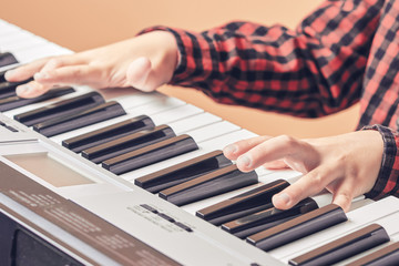 Obraz premium European kid is playing electric piano. He has his music lesson. Close view.
