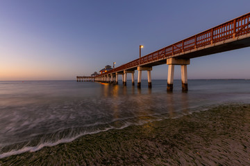 Fototapeta na wymiar Beautiful view of a wooden Pier on the Atlantic Ocean during a vibrant sunrise. Taken in Fort Myers Beach, Florida, United States.