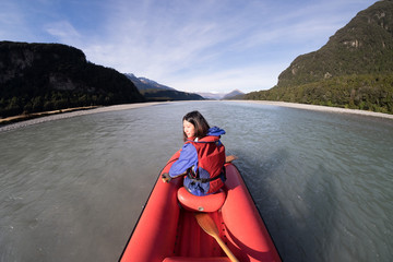 Young girl kayaking down a dart river of New Zealand. Girl traveling down river stream. Woman enjoying scenery. Lifestyle, adventure and exploration concept image. Recreation leisure activity