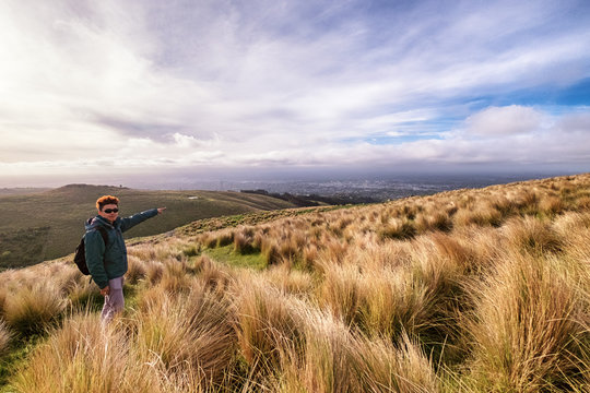A young traveler reached the top of port hill, Christchurch, New Zealand. Inspirational motivational concept image of a person standing on top of a mountain overlooking Christchurch city.