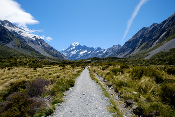 Fototapeta na wymiar A long straight gravel road that leads to the famous breathtaking snow mountain in Mount Cook, New Zealand. The landscape is epic. There are snow mountain, glacier, alpine, rivers and valley.