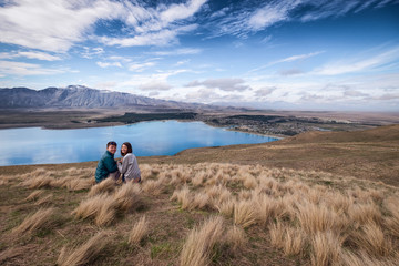 Fototapeta na wymiar Couple enjoys beautiful scenery in New Zealand. Romantic couple smiling into the camera. A pair of couple goes on honeymoon in natural landscape. Leisure image of a young couple in happiness.