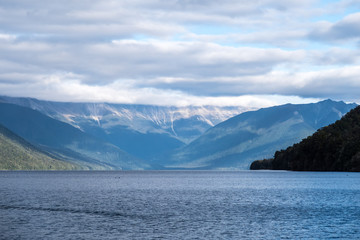 In a pristine New Zealand national park, this lake has astonishingly clear waters. The place is serene, peaceful and calming. This is suitable for background use. One can add text in the sky.