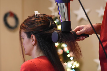 Hairdresser drying long hair with hair dryer. Making hairstyle for Christmas holidays. Concept of...