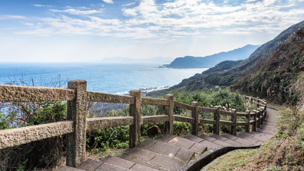 Fototapeta na wymiar This stunning view was taken in a popular hiking track in Taiwan. The stairs lead downhills along the edge of the cliff. The scenery has mountains and ocean. Steep drop provide exciting to visitors.