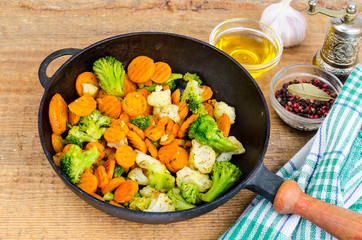 Stewed vegetables in oil on old pan, wooden table
