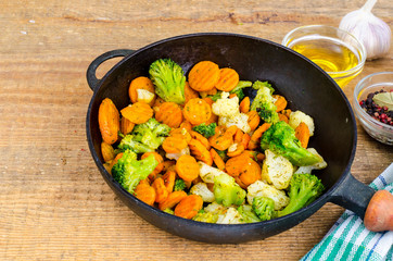 Stewed vegetables in oil on old pan, wooden table