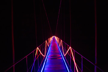 A neon bridge leads to empty darkness. Road leading to unknown mystery. Pathway to discovery and...