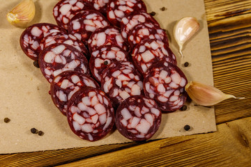 Sliced salami sausage on brown paper on wooden table