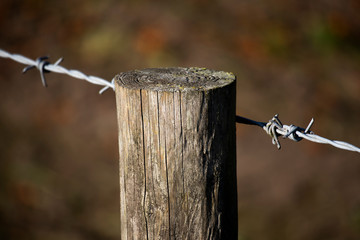 Barbed wired fence secured to post providing security to farmland in rural Hampshire