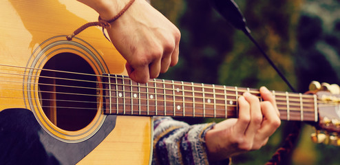 Young musician playing acoustic guitar close up